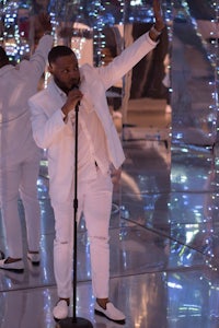 a man in a white suit singing into a microphone