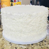 a white cake with coconut frosting sitting on top of a counter