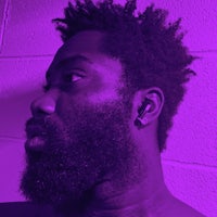 a man with a beard in front of a purple wall