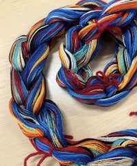 a blue, red, yellow, and orange yarn laying on a table
