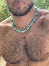 a man with a beard wearing a turquoise necklace