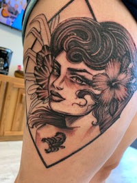a tattoo of a woman with flowers on her thigh
