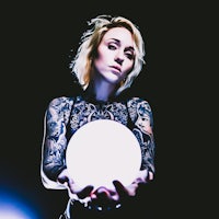 a woman with tattoos holding a crystal ball