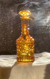 a yellow glass decanter sitting on a table in front of a window