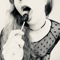 a black and white photo of a woman eating a lollipop