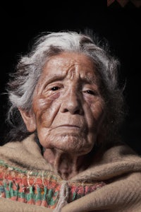 an old woman in a blanket with a black background