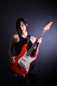 a woman holding a red electric guitar