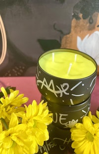 a black candle with yellow flowers next to it