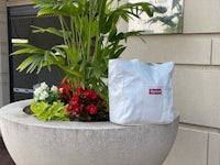 a white supreme bag sitting on a planter in front of a building