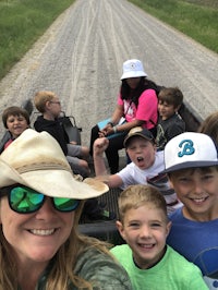 a group of kids riding in a truck on a dirt road
