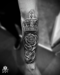 a black and white tattoo of a crown and roses