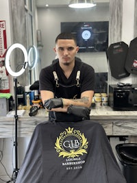 a man standing in front of a barber shop with a t - shirt