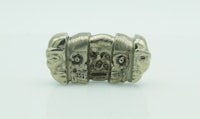 a silver ring with three skulls on it
