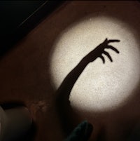 a shadow of a hand in a dark room
