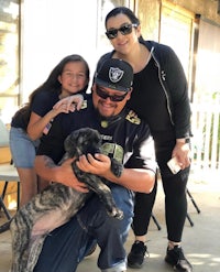 a family poses with a dog in front of a house