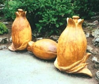 three carved wooden vases in a garden