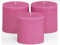 three pink pillar candles on a white background