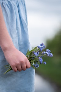 a girl is holding a bunch of blue flowers