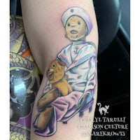 a tattoo of a girl with a teddy bear on her arm