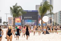 a crowd of people walking on the beach at a music festival