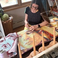 a woman is working on a piece of fabric