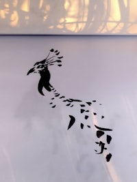 a black and white drawing of a peacock on a white surface