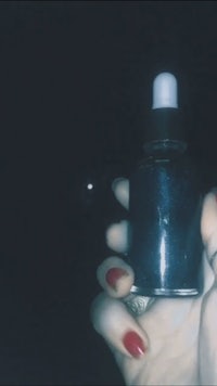 a person holding a bottle of black oil at night
