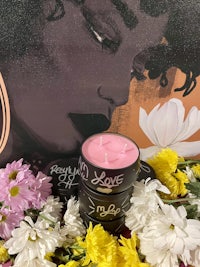 a pink candle surrounded by flowers and a painting