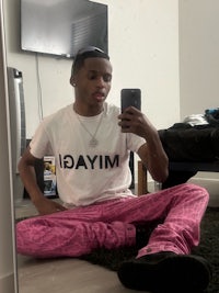 a man wearing pink pants and a t - shirt taking a selfie
