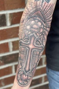 a man with a cross tattoo on his forearm
