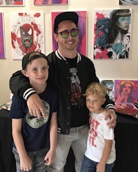 a man and two boys posing in front of a wall of art