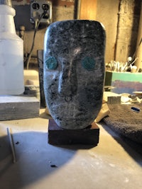 a stone head with green eyes sitting on a table