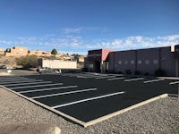 a black parking lot with a building in the background