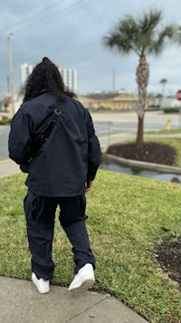 a person walking down a sidewalk in a black jacket and sneakers