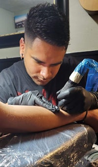 a man is getting a tattoo on his arm
