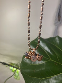 a necklace with a bead and a leaf hanging from it