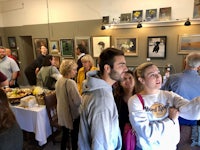 a group of people looking at paintings in a gallery