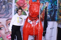 a woman standing next to a red dog statue