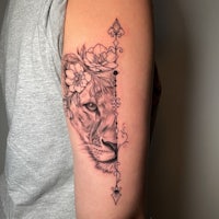 a tattoo of a lion with flowers on her arm