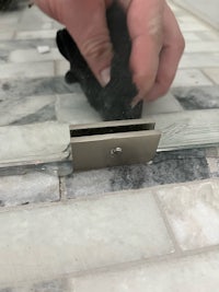 a person is removing a glass shelf from a tiled floor