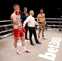 two boxers standing in a boxing ring with a referee