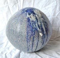 a blue and white ceramic ball on a white surface