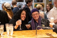 two people smiling at a bar with glasses of champagne