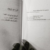 a hand holding a book with arabic writing on it