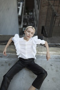 a woman in black leather pants and a white shirt laying on a roof