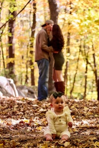 a man and woman with a baby in the woods