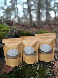 three bags of herbal tea sitting on a log in the woods