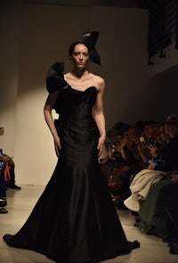 a woman in a black gown walks down the runway