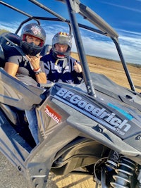 two people riding a polaris rzr xt in a dirt field