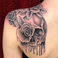 a woman's back tattoo with a skull and roses